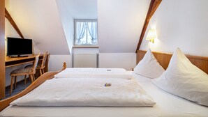 Une chambre d’hôtel avec deux lits, un bureau avec un ordinateur, une chaise et une fenêtre avec des rideaux.