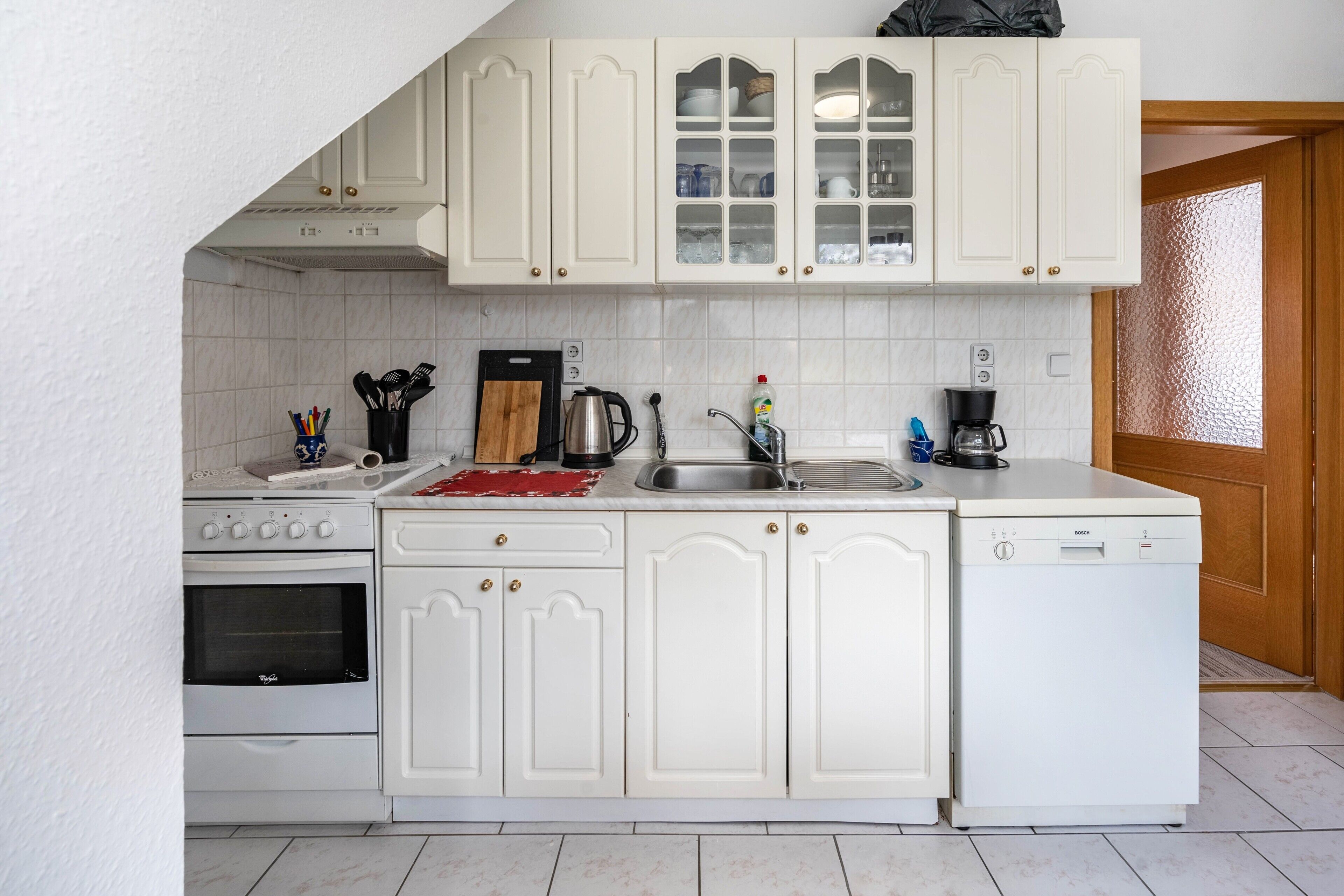 Una cocina con muebles blancos, un lavavajillas Bosch, una estufa y un fregadero.