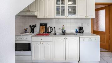 Una cocina con muebles blancos, un lavavajillas Bosch, una estufa y un fregadero.