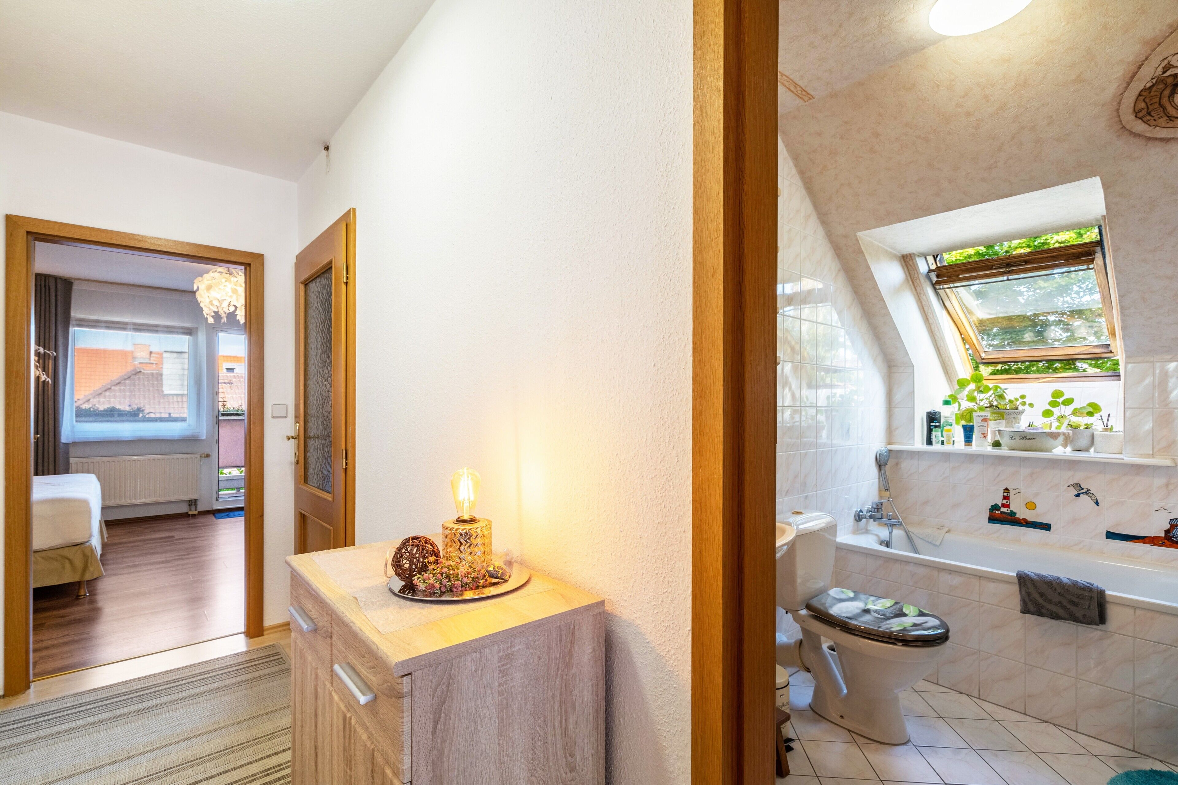 Une salle de bain moderne équipée d’une baignoire, de toilettes et d’une fenêtre donnant sur un espace verdoyant.