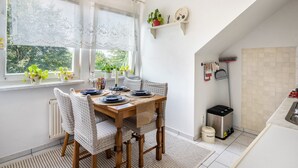 Un coin repas avec une table en bois, des chaises et une fenêtre agrémentée de plantes.
