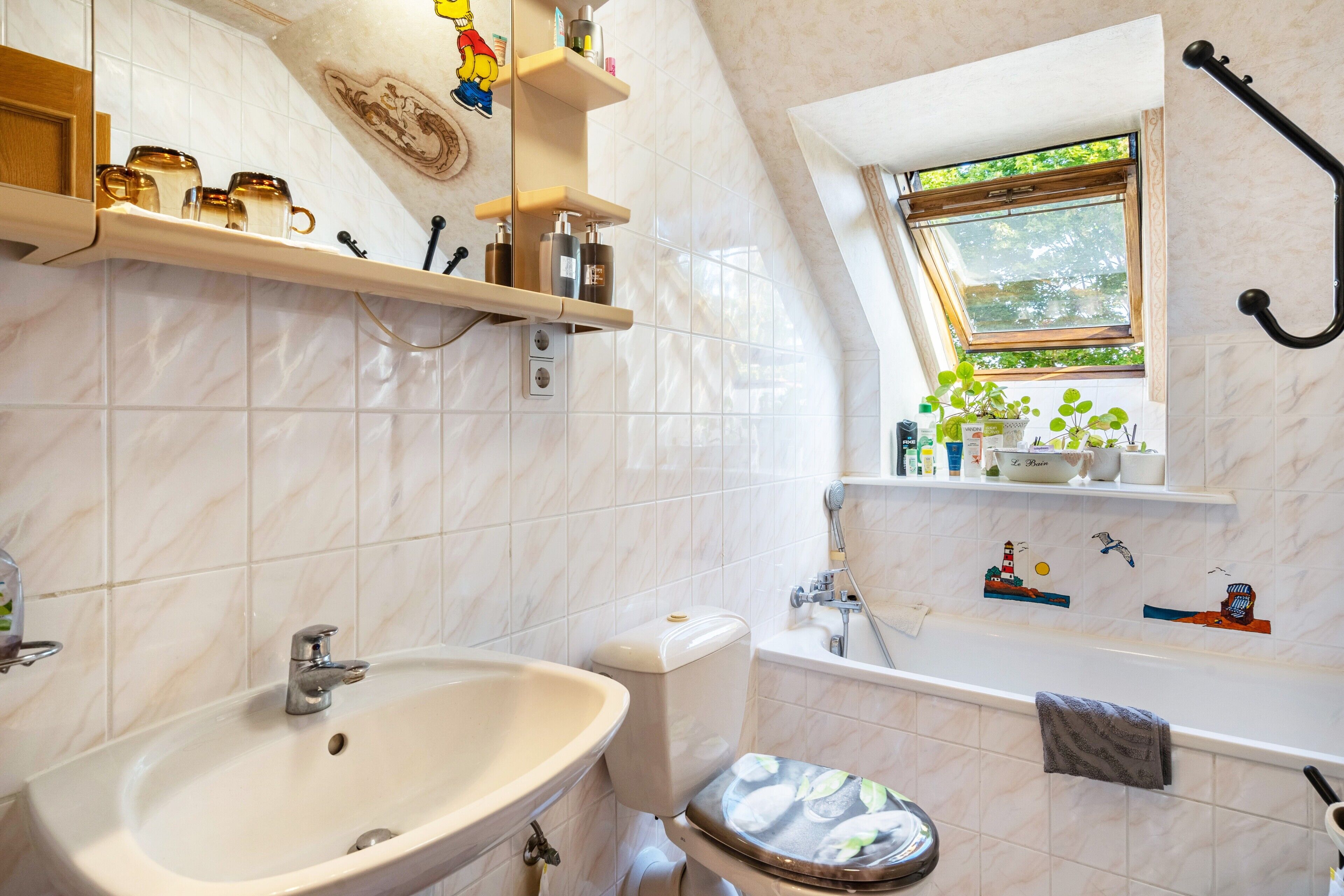 Ein Badezimmer mit Waschbecken, Toilette, Badewanne und einem Fenster mit Blick auf Grünflächen.