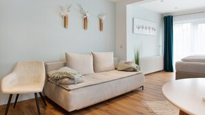 A living room with a sofa, a chair, a round table, and wall-mounted vases. - Studio Apartment 'No. 1' with Shared Garden and Wi-Fi (Bad Dürrheim)