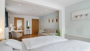 A hotel room with a bed, a desk, a chair, a sofa, and a radiator. - Studio Apartment 'No. 1' with Shared Garden and Wi-Fi (Bad Dürrheim)