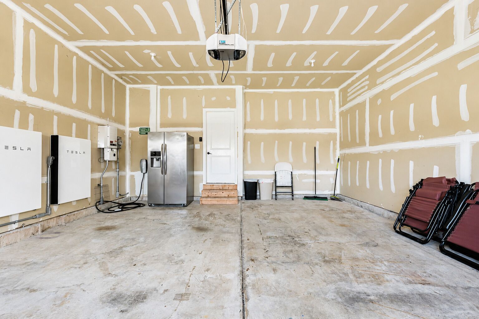 Ein Zimmer mit einem großen Kühlschrank, einem an der Decke befestigten Projektor und einer Tür zu einem weiteren Raum.