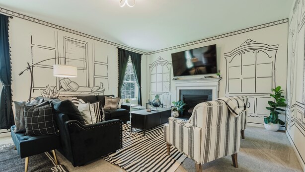 A living room with a black sofa, a striped armchair, a coffee table, and a fireplace. - Unique 2D-Style Family Retreat (Pennsburg)
