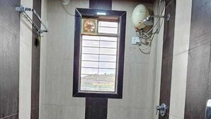 A bathroom with a wooden ceiling, a window, a toilet, and a hand basin.