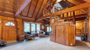 A spacious log cabin with a high ceiling, a staircase, and a cozy seating area with a fireplace. - Riversong Lodge by AvantStay | Sauna + Hot Tub | On The Truckee River (Truckee)