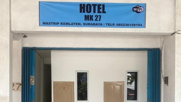 Ingresso di un hotel con due porte, un tendone blu e un cartello che indica Wi-Fi gratuito.