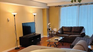 Ein modernes Wohnzimmer mit einem Glastisch, einer Ledersofa und einem Flachbildfernseher.