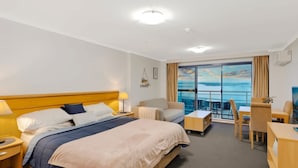 A hotel room with a bed, a desk, a chair, and a balcony with a view of the sea. - The Entrance Waterfront Resort, Unit 614 (The Entrance)