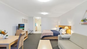 A hotel room with a bed, a sofa, a desk, and a TV. - The Entrance Waterfront Resort, Unit 614 (The Entrance)