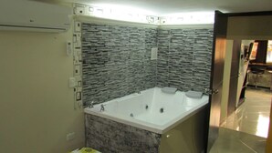 A bathroom with a large bathtub, tiled walls, and a visible toilet. - One Bedroom AC Hot Tub 1 block Parque Poblado (Medellin)