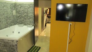 A bathroom with a large bathtub, two sinks, and a flat-screen TV mounted on the wall. - One Bedroom AC Hot Tub 1 block Parque Poblado (Medellin)