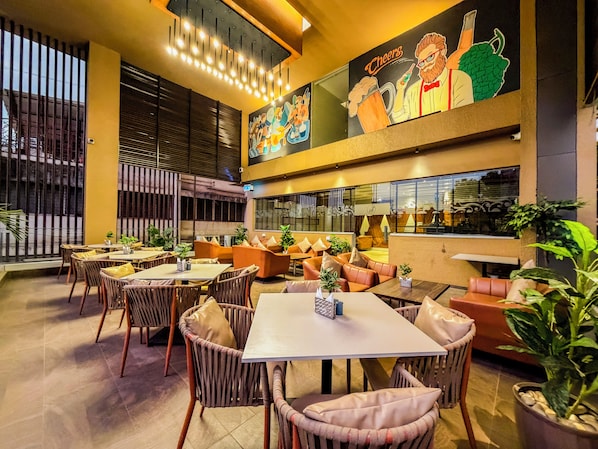 A restaurant with indoor seating, a large mural, and a view through the windows. - Zip By Spree Hotels Kolhapur (Kolhapur)