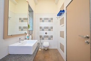 A bathroom with a white sink, a toilet, and a shower. There is a mirror above the sink and a towel rack above the shower.