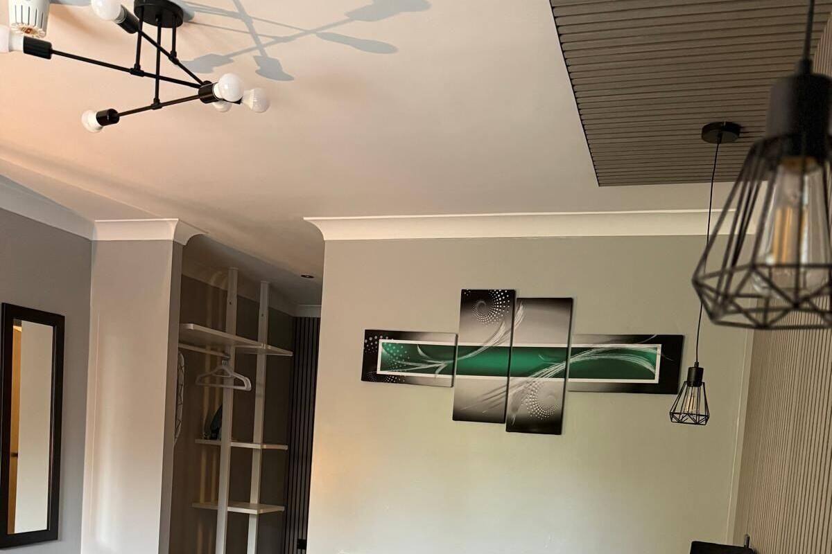 A bedroom with a bed, a radiator, a wardrobe, and a ceiling light fixture.