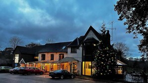 A building with a parking lot, a Christmas tree, and a small adjacent structure. - The Jacobean Hotel (Coventry)