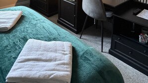 A hotel room with a bed, a desk, a chair, a TV, a dresser, and a window. - The Jacobean Hotel (Coventry)