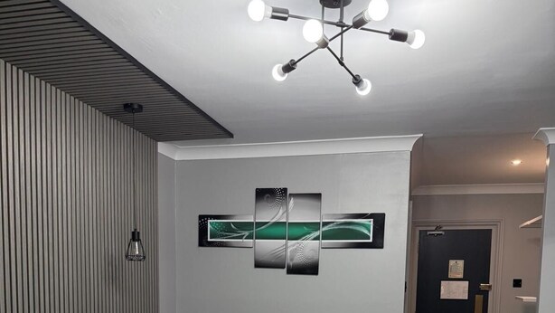 A modern hotel room with a bed, a radiator, a wall-mounted artwork, and a ceiling light fixture. - The Jacobean Hotel (Coventry)