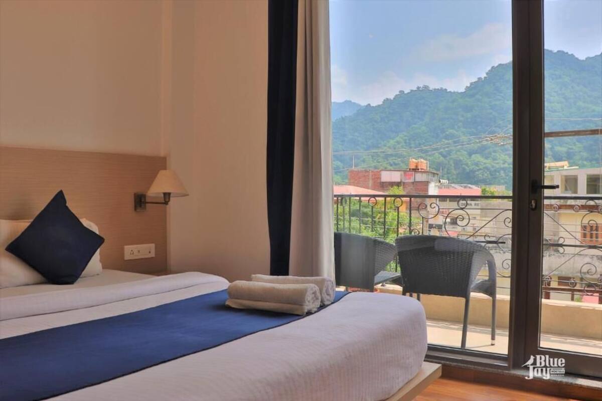 Una habitación de hotel con una cama, una silla y vistas a una montaña y edificios.