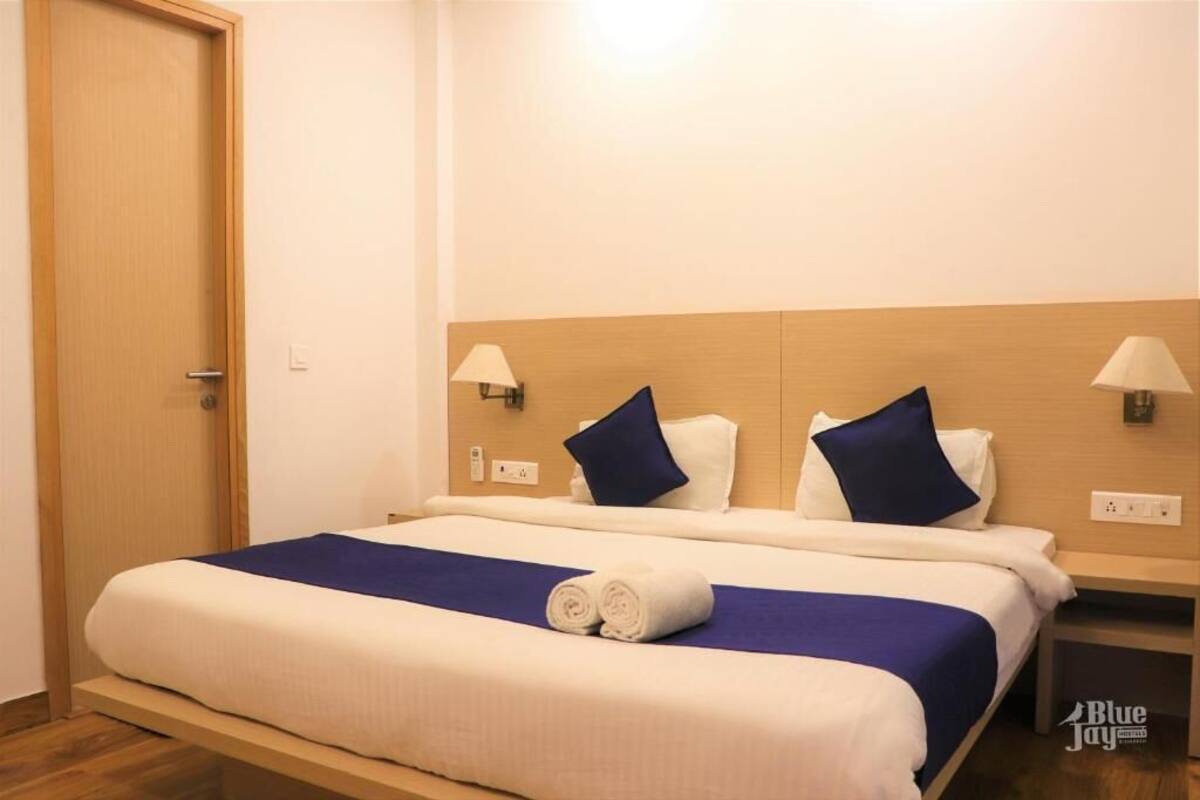 Una habitación de hotel con una cama, dos almohadas, una manta azul y un par de toallas enrolladas.