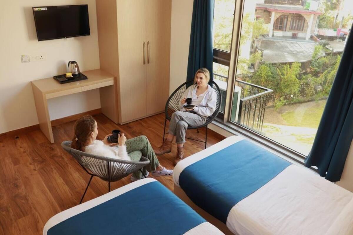 Una habitación con dos camas, un escritorio, una silla y un televisor.