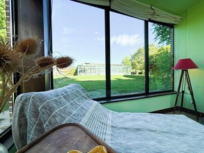 Enjoy a peaceful retreat with a garden view from the large window, a comfortable bed, and a small table for relaxation.