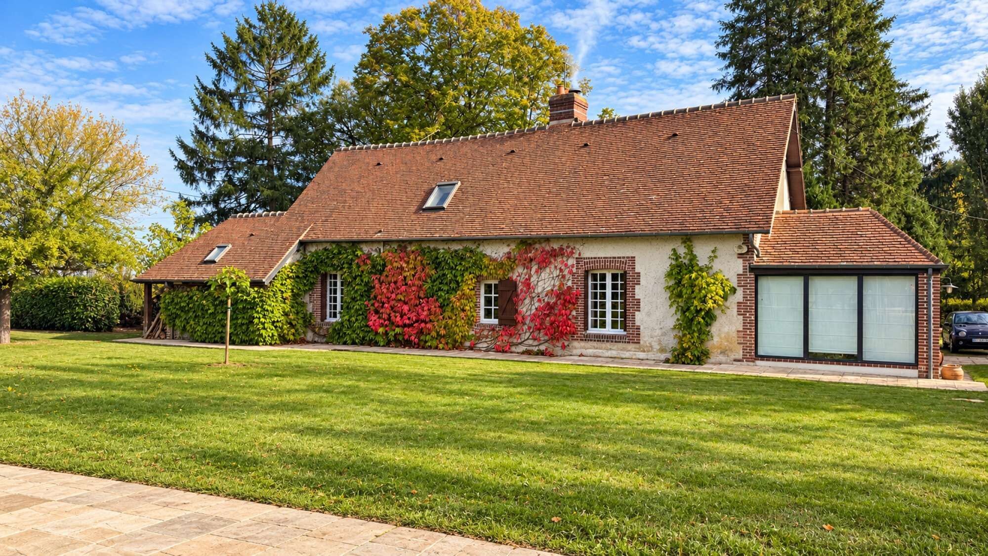 Une maison à deux étages avec un toit en pente, une véranda et un garage.