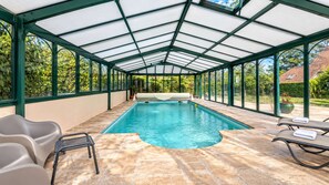 A covered swimming pool with a glass ceiling, stone flooring, and lounge chairs. - La Maison du Tilleul with a pool for 10 people (Saint-Sulpice-sur-Risle)