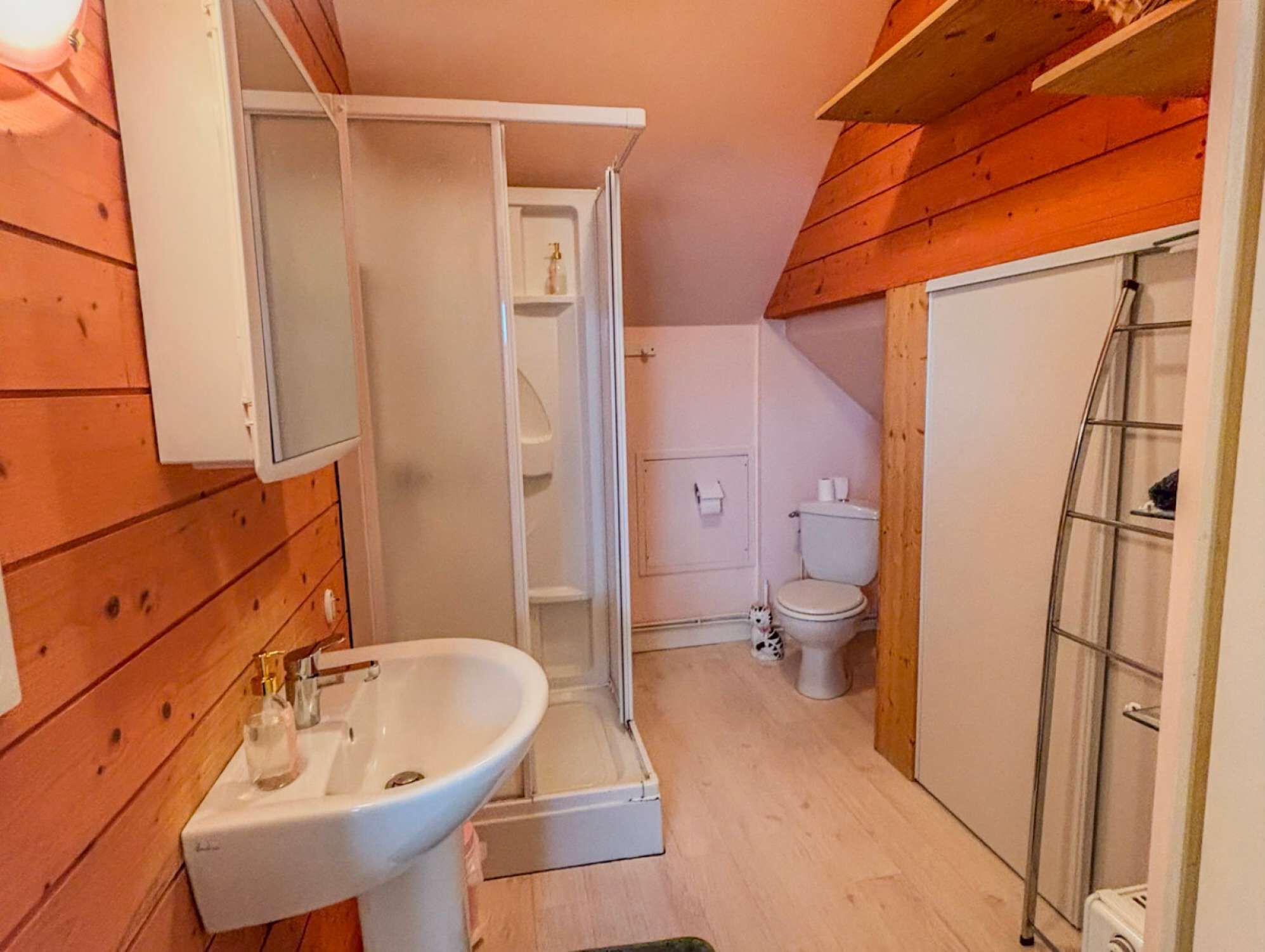 A compact bathroom with a sink, toilet, and shower.