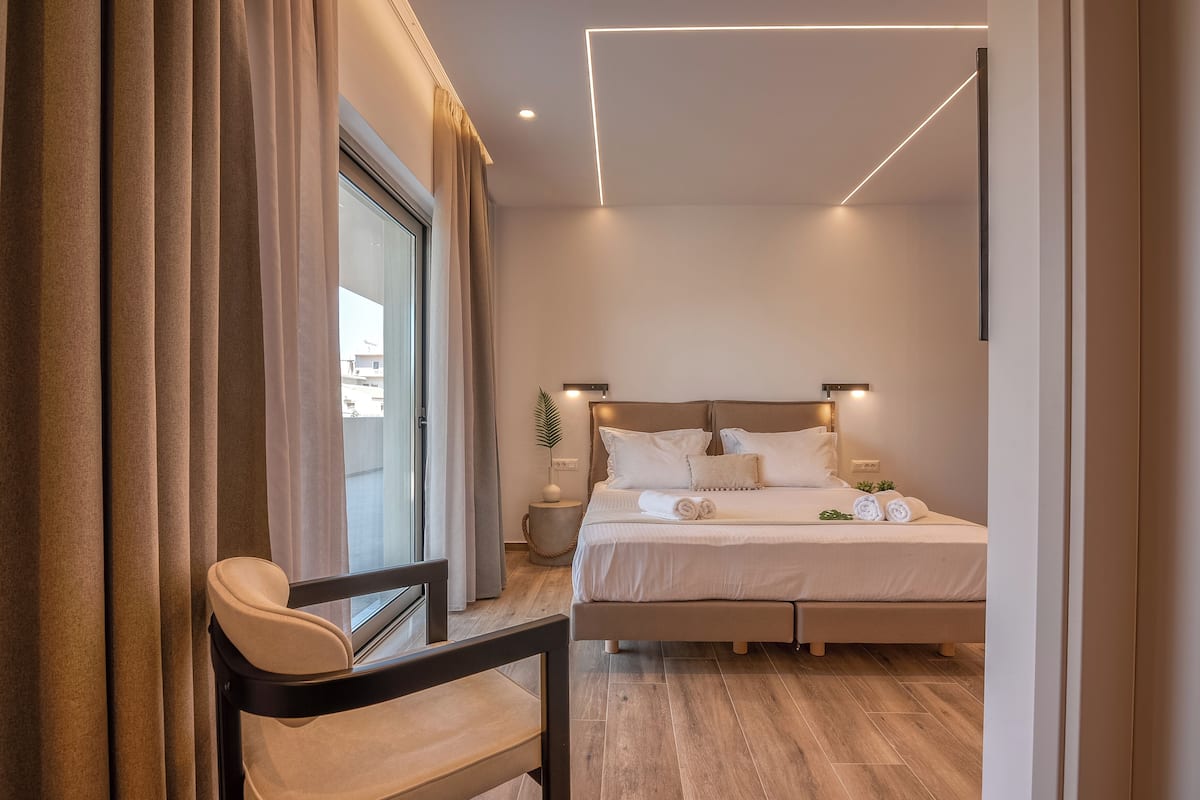 A modern bedroom with a large bed, bedside lamps, and a view through a window with curtains.