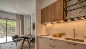A modern kitchen with white cabinets, a wooden upper shelf, and a sink. - kiwi butique studios (Kissamos)