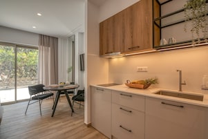 A modern kitchen with white cabinets, a wooden upper shelf, and a sink.