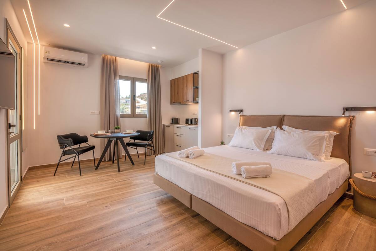 A modern hotel room with a large bed, a desk, and a dining area.