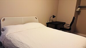 En pænt redt seng med et hvidt sengetæppe i et hotelværelse.