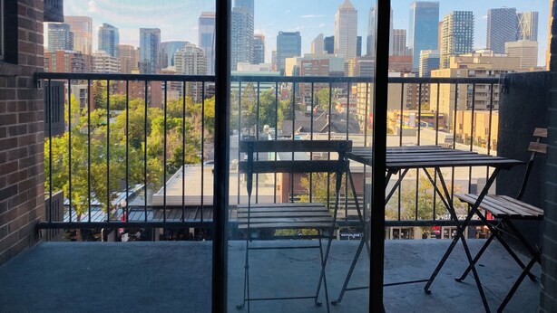 En balkon med udsigt over byens skyline, et bord og en stol.