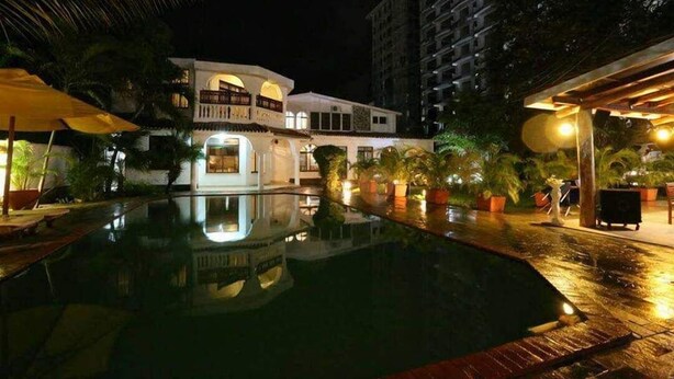 A nighttime view of a hotel with a swimming pool, palm trees, and a well-lit outdoor area. - Pontoon Residence & Suites (Mombasa)