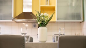 A dining table with a vase of flowers, two wine glasses, and a modern kitchen in the background. - La Casa di Riccardo Cosy in Center Town (Lucca)