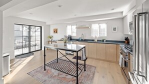 A modern kitchen with a central island, wooden cabinets, and a stainless steel refrigerator. - Downtown Villa with Private Spa (Bend)