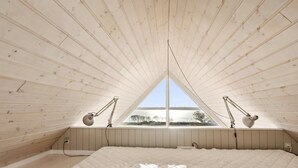 Un dormitorio con una cama grande, techo de madera y ventana con vistas a un lago.