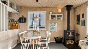 Una cocina acogedora con una mesa de comedor, sillas, una estufa y un ventanal.