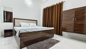 A bedroom with a bed, a nightstand, a wardrobe, and a mirror. - Bharat Raj Homestay By GRB (Faizabad)