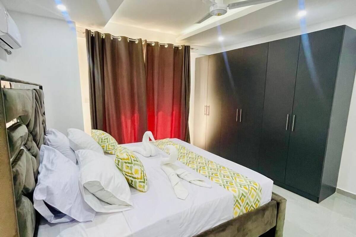 A modern bedroom with a bed, a ceiling fan, and a wardrobe.