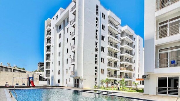 Een modern appartementencomplex met een zwembad ervoor.