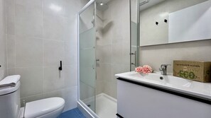 A bathroom with a toilet, a shower, and a sink.