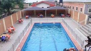 A rectangular pool with a metal railing, surrounded by outdoor seating with tables and chairs. - Hotel Seventeen (Kaduna)