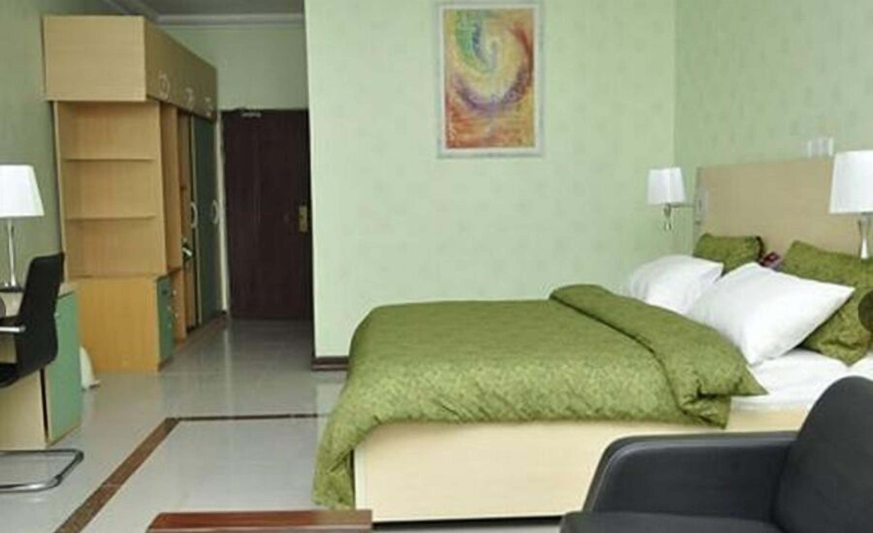Une chambre d’hôtel avec un lit, un bureau et une chaise. Une porte donne accès à une autre pièce.