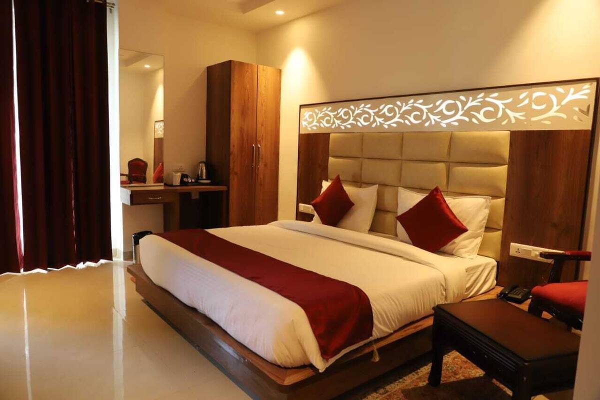 A hotel room with a large bed, a wooden wardrobe, a bedside table, and a mirror.