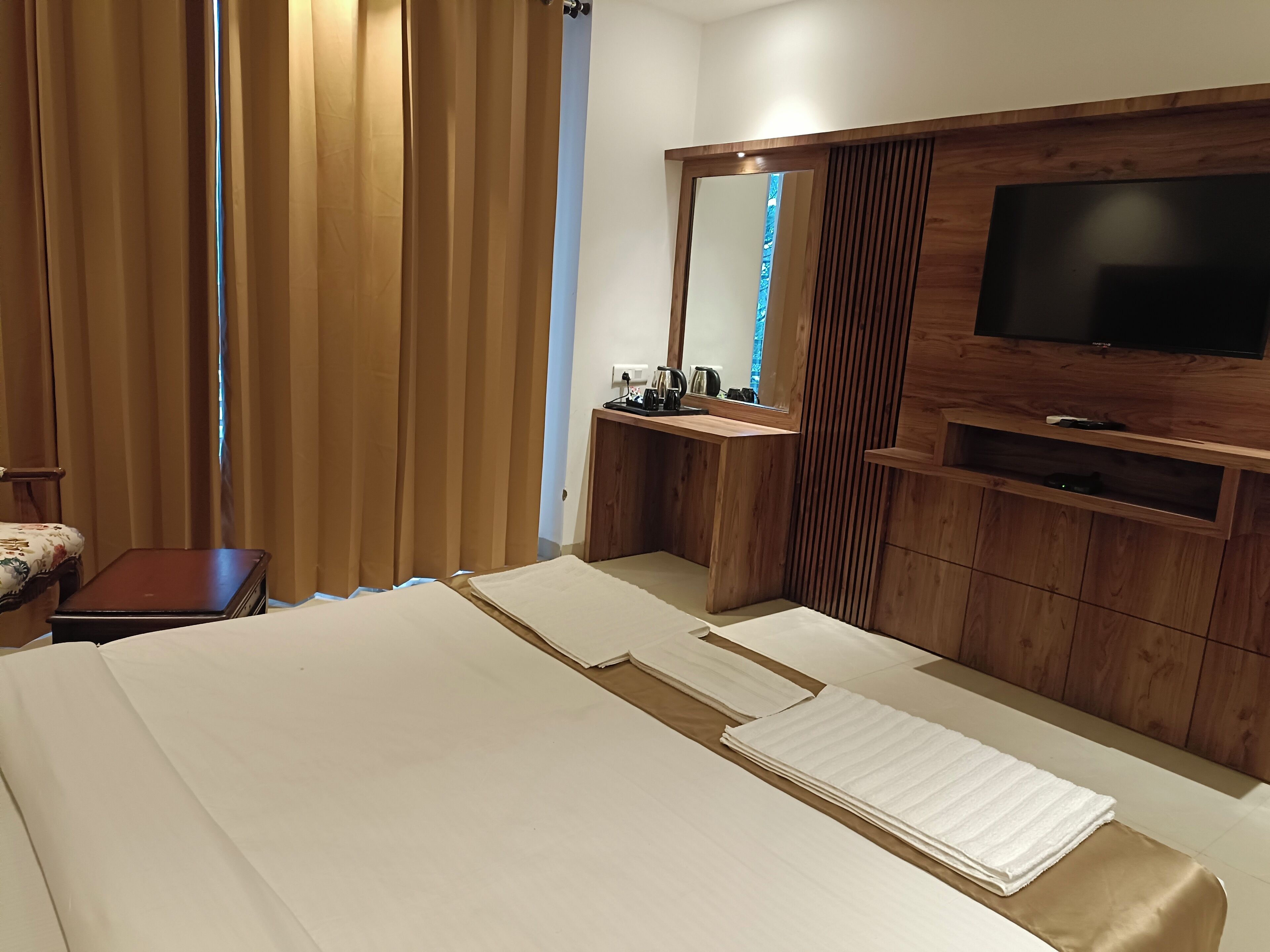 A hotel room with a bed, a TV, a wooden cabinet, and a small table.